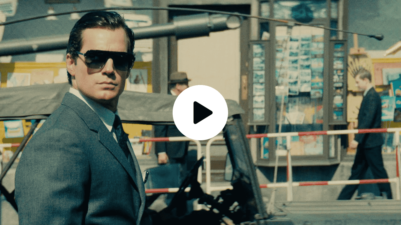 Scene from The Man from U.N.C.L.E. showing Henry Cavill in a sharp suit and dark sunglasses, exuding cool confidence in a Cold War-era European street setting, reflecting the film’s sleek spy thriller aesthetic.